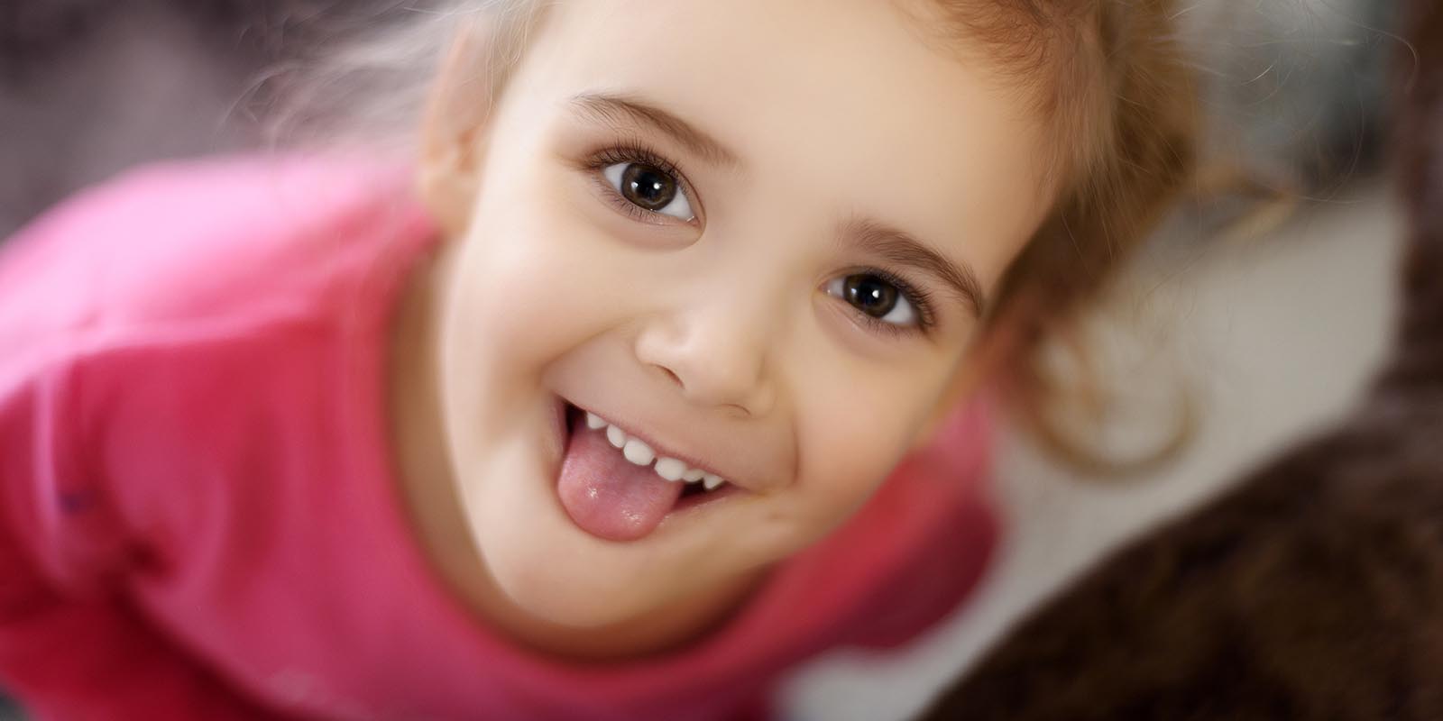 Child playfully sticking tongue out at camera, Adobe Stock.