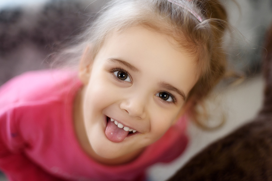 Child playfully sticking tongue out at camera, Adobe Stock.