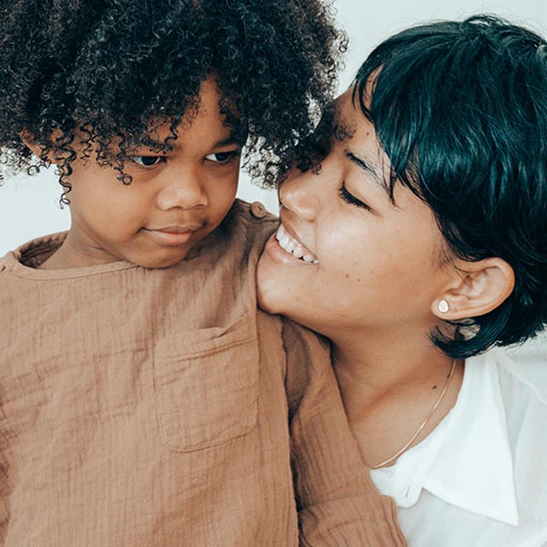Parent or caregiver hugging young child and smiling, credit Ketut Subiyanto - Pexels.