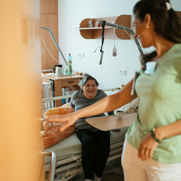 Health care provider talking with hospital patient seated on bed, credit – Jsme MILA, Pexels. 