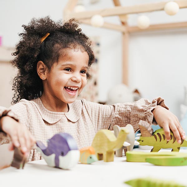 Joyful child seated at a table playing with toys, Cottonbro – Pexels.
