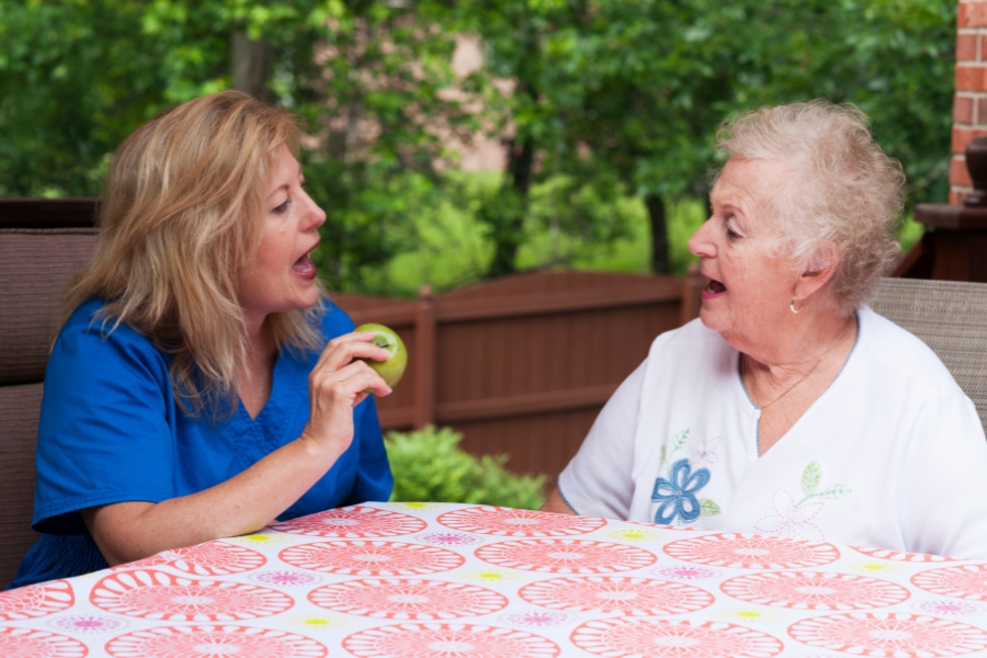 Provider holds up an apple, speaking to an elderly patient.