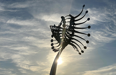 SOAR kinetic wind sculpture (AZLON, artist Anthony Howe) at the UNMC Munroe-Meyer Institute, backlit against sun and blue sky filled with cirrus clouds; photo credit: Karoly Mirnics PhD MD