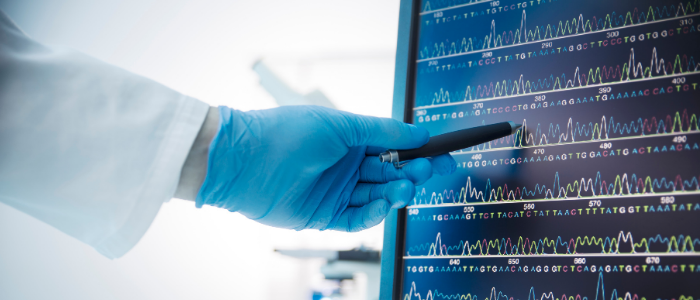 stock photo of scientist pointing a gloved hand holding a pen to a computer screen showing DNA sequence; credit: Canva
