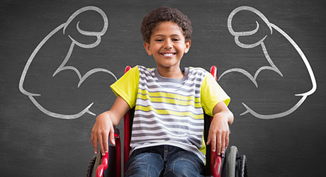 : stock photo of adolescent child sitting in a wheelchair smiling, in front of a chalkboard with chalk-drawn muscled arms flexed in a power pose; credit: Shutterstock