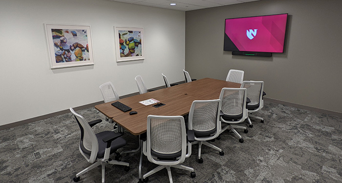 Medium conference room, MMI 40042, tables pushed together in center of room with 10 chairs on outer edge, computer, keyboard, mouse, large flat screen TV.