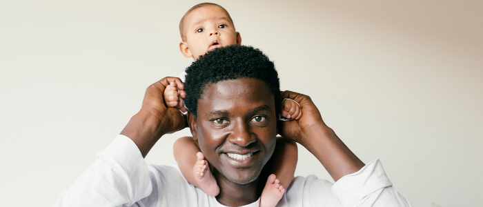 stock photo of man baby on his shoulders, holding baby's hands, smiling; credit; Canva