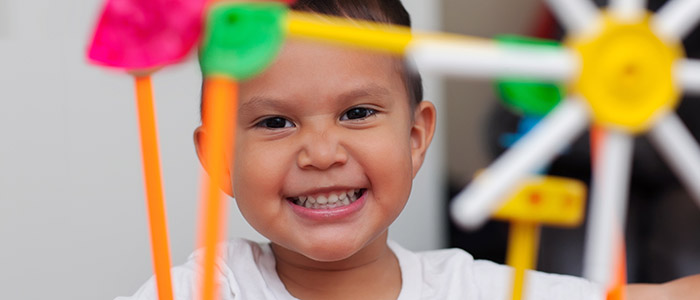stock photo of young boy, smiling through colorful k'nex toys; credit: Adobe