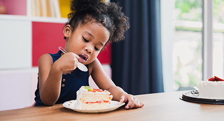 stock photo of young girl eating a piece of white cake with strawberry filling; credit: iStock