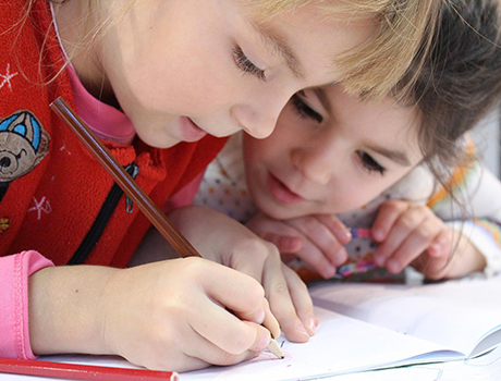 Two school-aged kids writing in a workbook, credit KLimkin - Pixabay.
