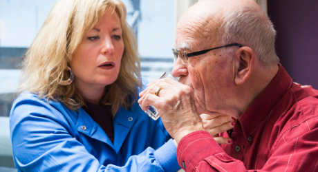 speech-language pathologist working with an older patient on swallowing water; stock photo credit: Canva
