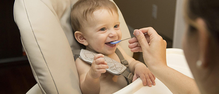 Happy baby being fed in feeding chair, credit Pixabay.