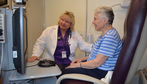 Claudia Chaperon, Ph.D., and a patient consult with a specialist via the telehealth network from the mobile nurse clinic.