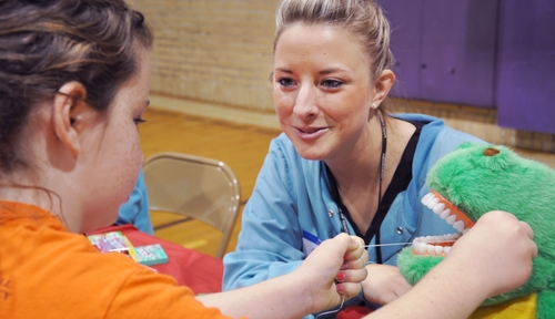 Casey Filbert, a third-year dental  student, teaches a child how to floss properly.