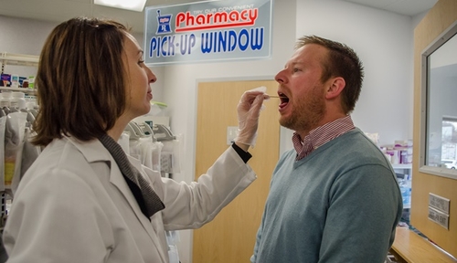 Hy-Vee pharmacist, Tori McCarthy, performs a rapid strep test on Donald Klepser of UNMC.