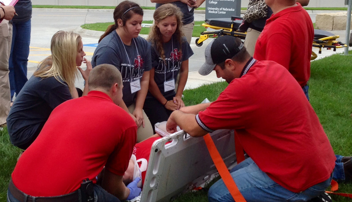 In blue from left to right, students Morggan Key, Skyler Gamble, and Alyssa Beller learning how to assess and move a patient at the UNMC College of Nursing Northern Division's weekend camp.