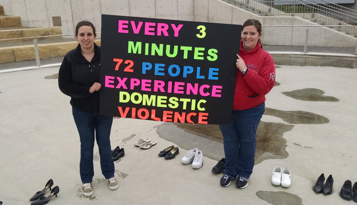 EMPOWER student leaders Jessica Semin, left, and Sarah Vetter at the Domestic Violence Awareness Month shoe drive display at the ice rink on the Bill and Ruth Scott Student Plaza.