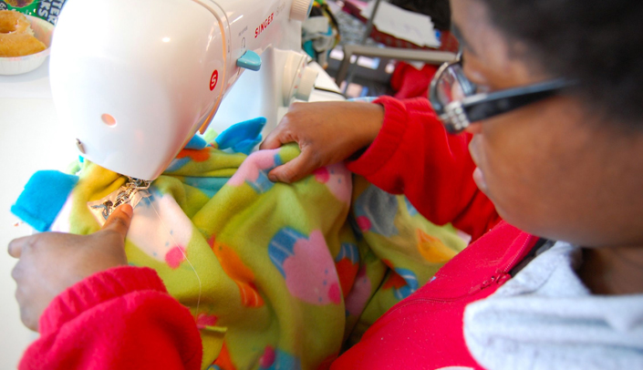 College of Nursing student Destinee Myres attaches a Project Linus tag to one of the 200 fleece blankets constructed Tuesday for the Project Linus group.