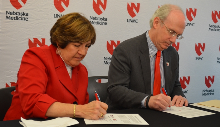Marsha Lommel, president and CEO of Madonna Rehabilitation Hospital, and Jeffrey P. Gold, M.D., chancellor of UNMC and chairman of Nebraska Medicine, sign the agreement that will establish the partnership between the two organizations.