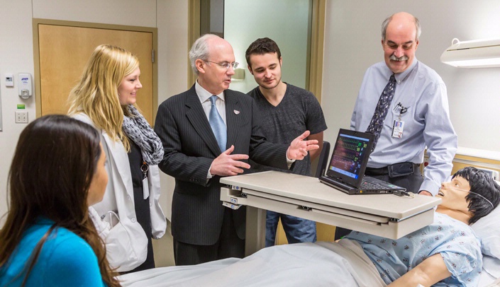 UNMC Chancellor Jeffrey P. Gold, M.D., center, and Paul Paulman, M.D., professor of family medicine, right, with medical students in the simulation lab.