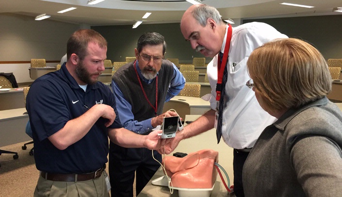 From left, Jonathon Sample, simulation associate, John Adams, Ph.D., associate professor, College of Public Health health services research and administration, Paul Paulman, M.D., professor of family medicine and faculty development coordinator Linda Love examine portable ultrasound equipment and a simulation model at the Education Technology Collaboration meeting held earlier this month.