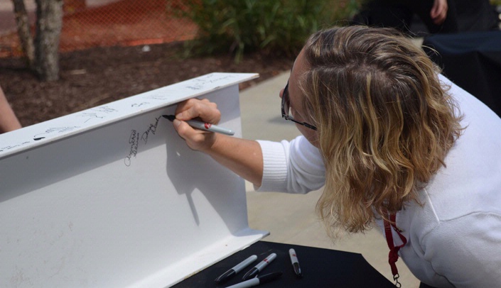 A UNMC staff member signs a beam for the Fred & Pamela Buffett Cancer Center's beam-raising ceremony. The cancer center was one of several major construction projects on University of Nebraska campuses that are being supported with the help of private gifts.