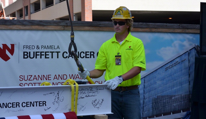 A construction prepares to raise a beam to the top floor of the Fred & Pamela Buffett Cancer Center.
