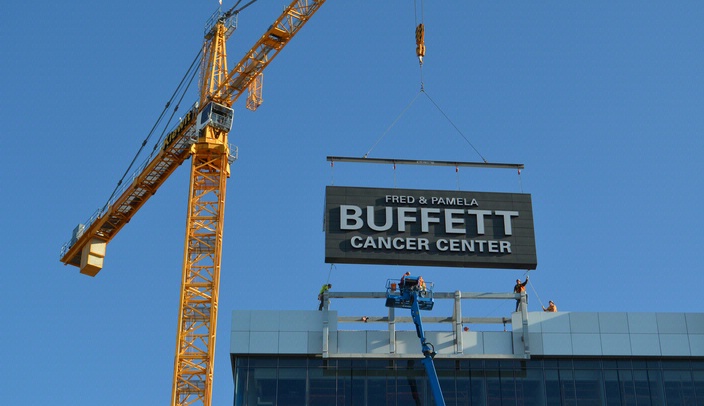 Workers put the sign on the south side of the Fred & Pamela Buffett Cancer Center into place.