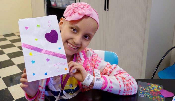 Eight-year-old Daisy Anguiano Miranda, a Ewing's sarcoma survivor, displays a luminaria she designed.