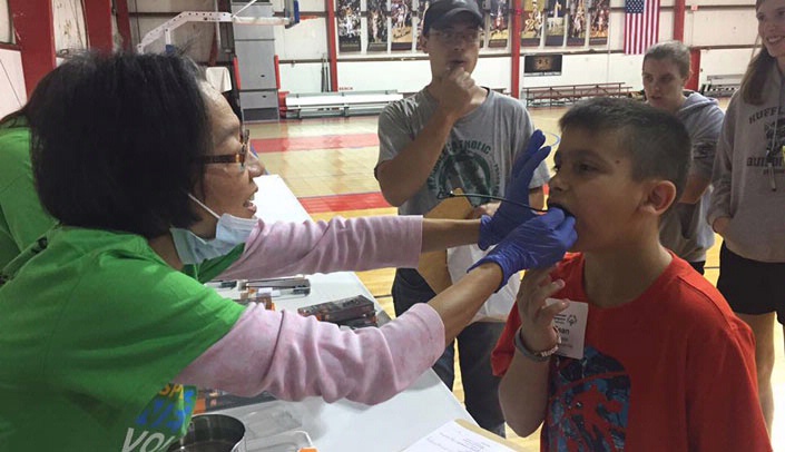 Ellen Hahn, D.D.S., Ph.D., fits a young athlete with a mouth guard during the Aug. 6 Special Smiles Healthy Athlete event, held in conjunction with the fall games of Special Olympics Nebraska.