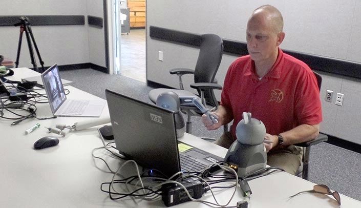 From a conference room in the Johnson Space Center in Houston, Clayton Anderson uses remote controllers to move the "hands" of a surgical robot nearly 900 miles away in Omaha. He is watching a video feed that allows him to see what he is doing.