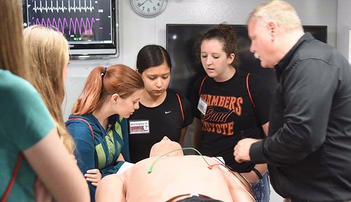 High school students participated in "Be a Paramedic" as part of the Health and Wellness Summer Career Camp. Pictured (from left) are Kaylee Hilton, South Sioux City, Neb., MorningStar Roundstone, Pender, Neb., Kyra Farewell, Ewing, Neb., and Doug Dekker, Simulation Program Liaison for Simulation in Motion-Nebraska at UNMC. (Courtesy Northeast Community College)