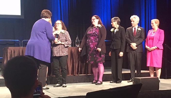 Mary Helms, second from left, receiving her award from Medical Library Association President Theresa Knott, left.
