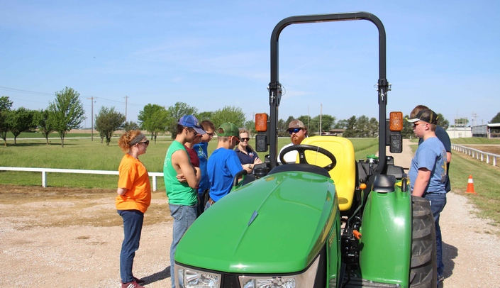 UNMC graduate student Dan Kent (center) discusses with young farmers the importance of seat belts and rollover protection structures.