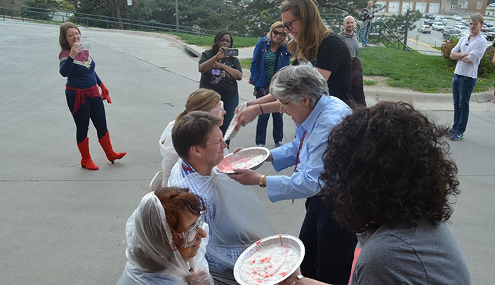 From bottom, Bhavana Dave, Ph.D., Scott Smith, Ph.D., and Jennifer Sanmann, Ph.D., prepare to get pied after a successful flood-relief fundraiser at the Munroe-Meyer Institute's Human Genetics Lab.