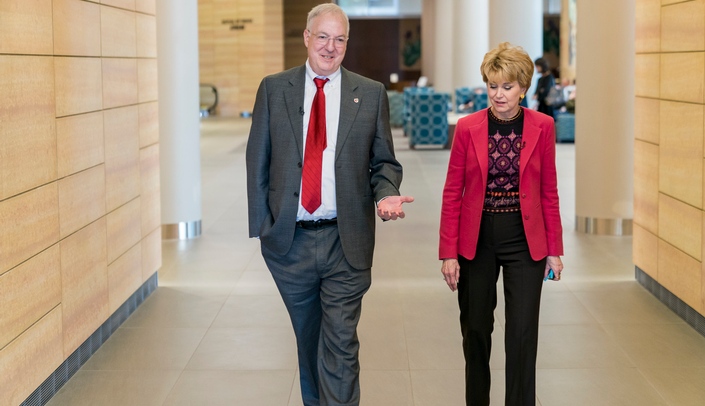 Ken Cowan, MD, PhD, walks with legendary reporter Jane Pauley down a hallway of the Fred & Pamela Buffett Cancer Center in 2017.