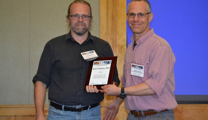 Dr. Rytis Prekeris, at left, receives a plaque in recognition of his accomplishments from long-time friend Dr. Steve Caplan, of UNMC.