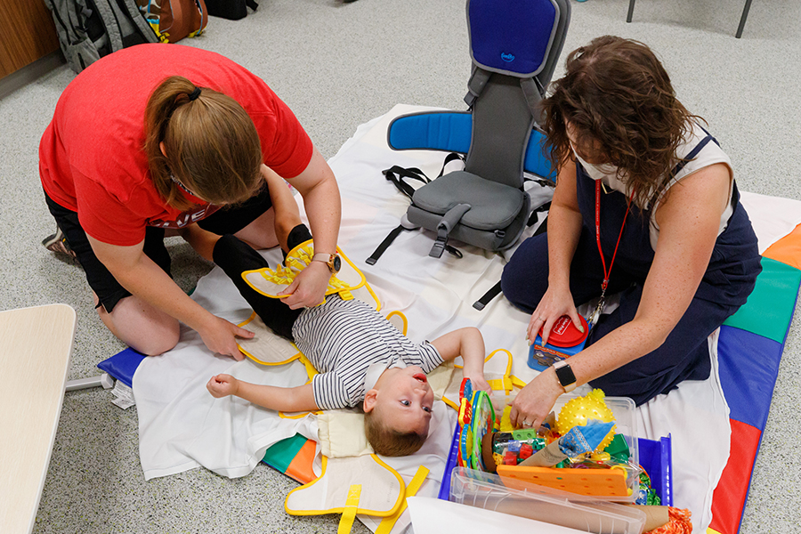 Tonya Hinrichs secures Bentley into his ZeroG harness as occupational therapist Sarah Birkel looks on.