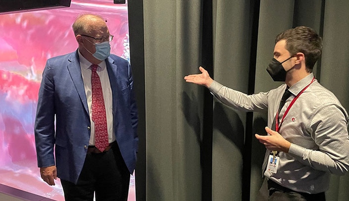 Omaha Councilman Don Rowe, left, speaks with UNMC's Michael Hollins about iEXCEL's Five-Sided Laser CAVE.