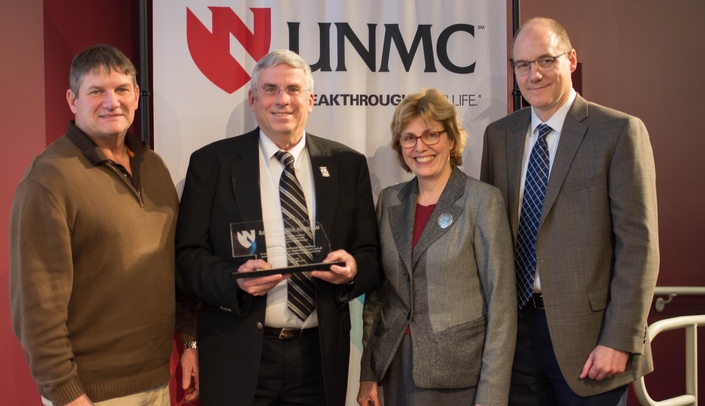 Joe Krajicek, left, was on hand to congratulate his longtime colleague, Steve Dixon, DVM, then director of UNMC Comparative Medicine, at the 2016 Distinguished Scientist ceremony. At right are Jennifer Larsen, MD, UNMC vice chancellor for research, and Ken Bayles, PhD, associate vice chancellor for basic science research.