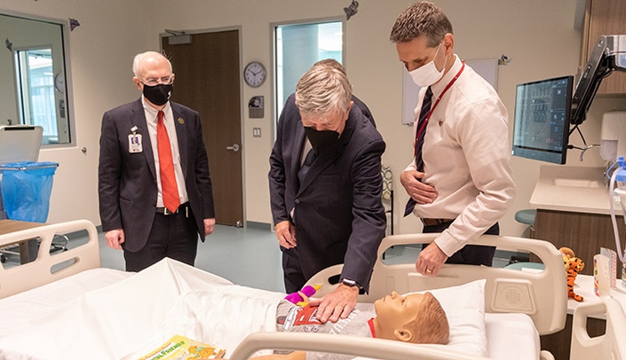 Daniel Mulhall, the Irish ambassador to the United States, checks the heartbeat of a simulated patient as UNMC Chancellor Jeffrey P. Gold, left, and Benjamin Stobbe, assistance vice chancellor of clinical simulation, look on.