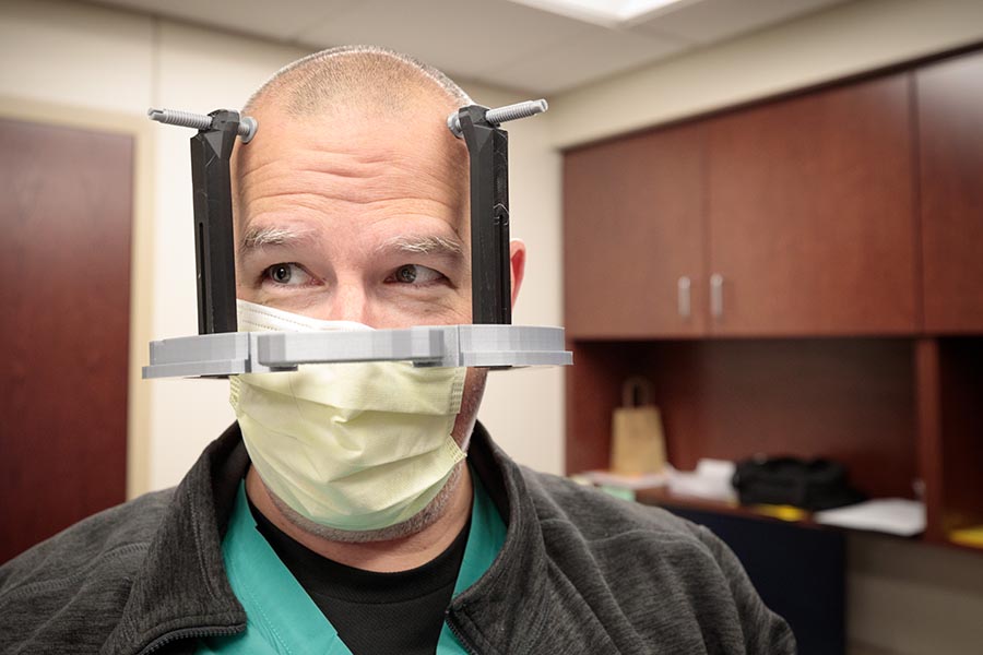 Dennis Rieke, physician assistant with the UNMC Department of Neurosurgery, models the 3D-printed stereotactic head frame.