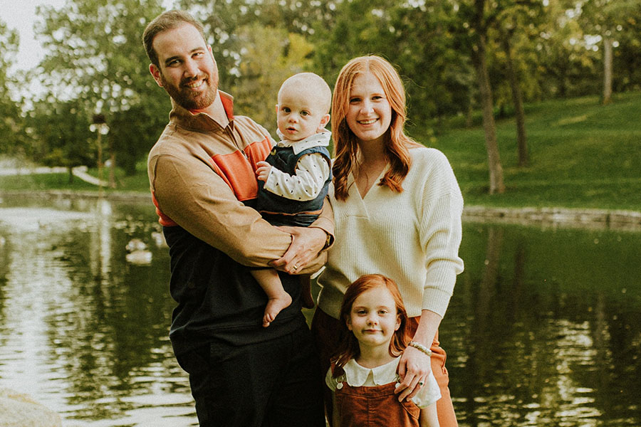 Grace Handeleman poses with her family in front of a body of water..