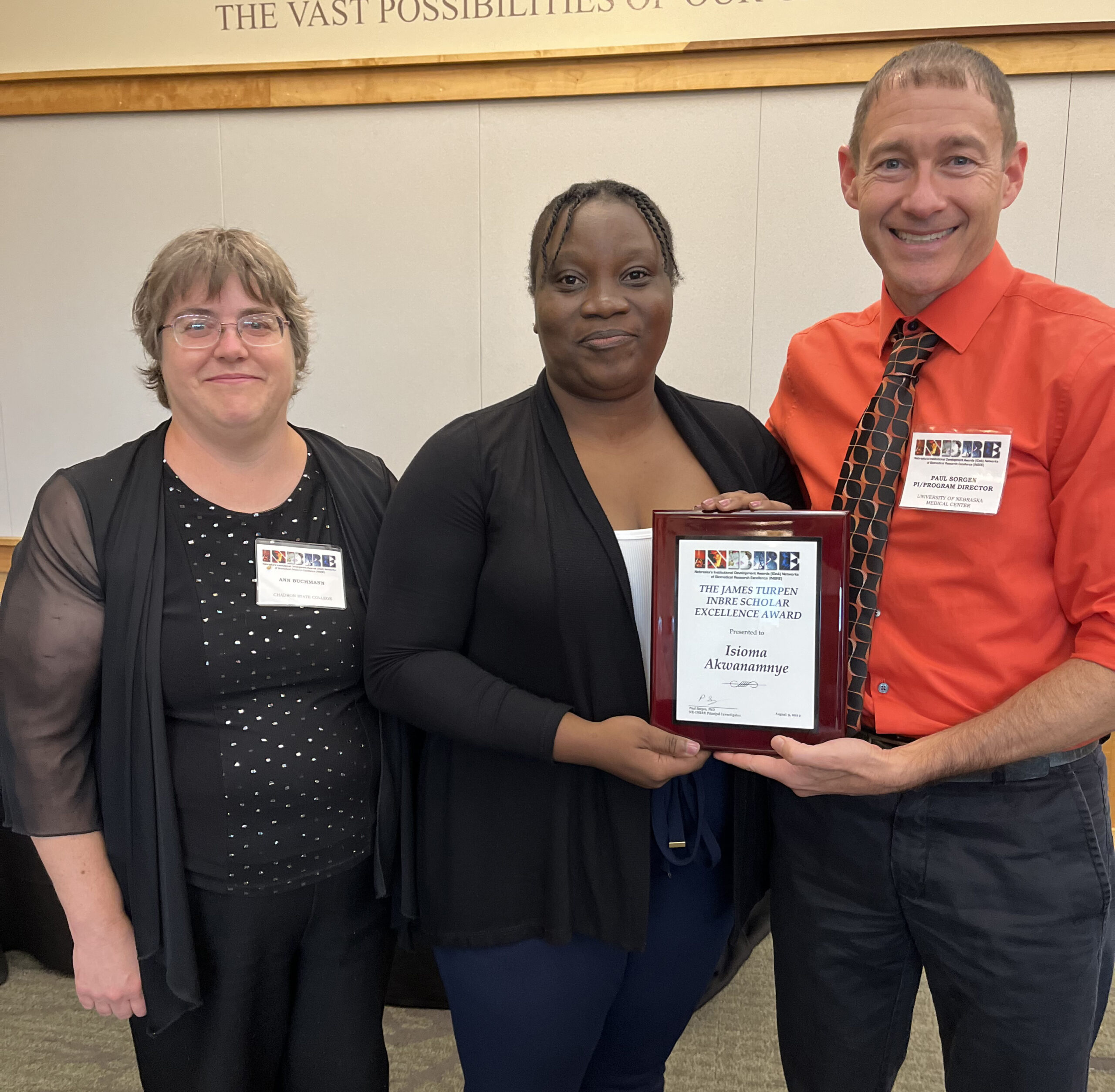 Dr&period; Paul Sorgen&comma; far right&comma; presents the James Turpen INBRE Scholar Excellence Award to Isioma Akwanamnye&comma; a senior at Chadron State College&period; Standing next to Isioma is her mentor&comma; Dr&period; Ann Buchmann&period;