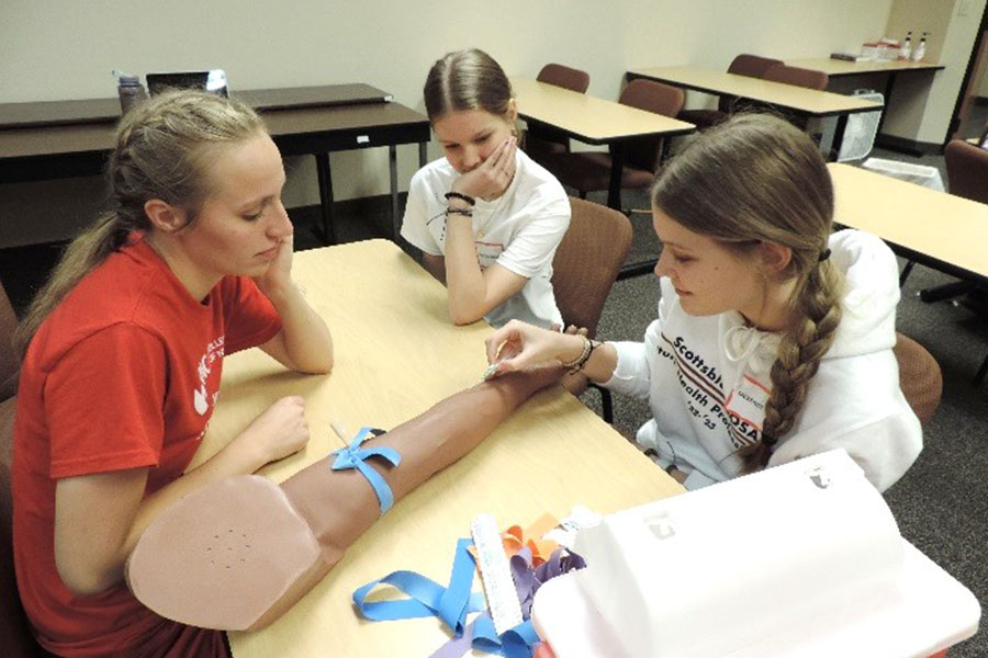 Nursing student Jessica Ragonese watches as a HOSA student practice IV insertion&period;