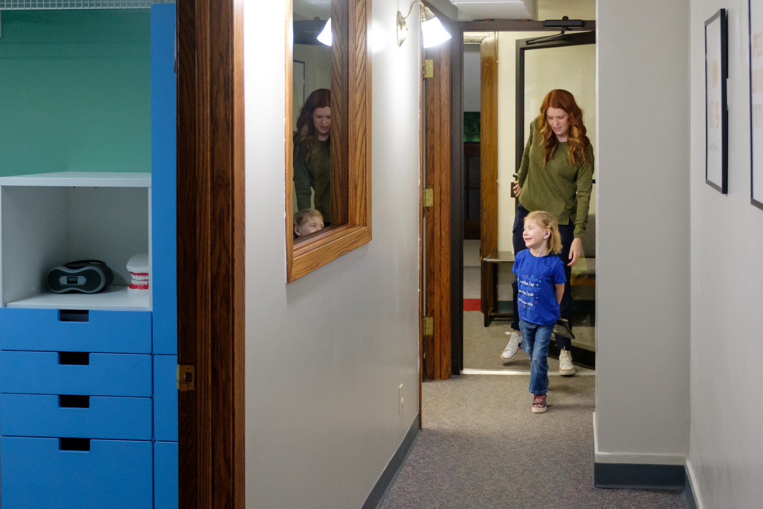 Therapist and young client walk down a hallway to their therapy room.