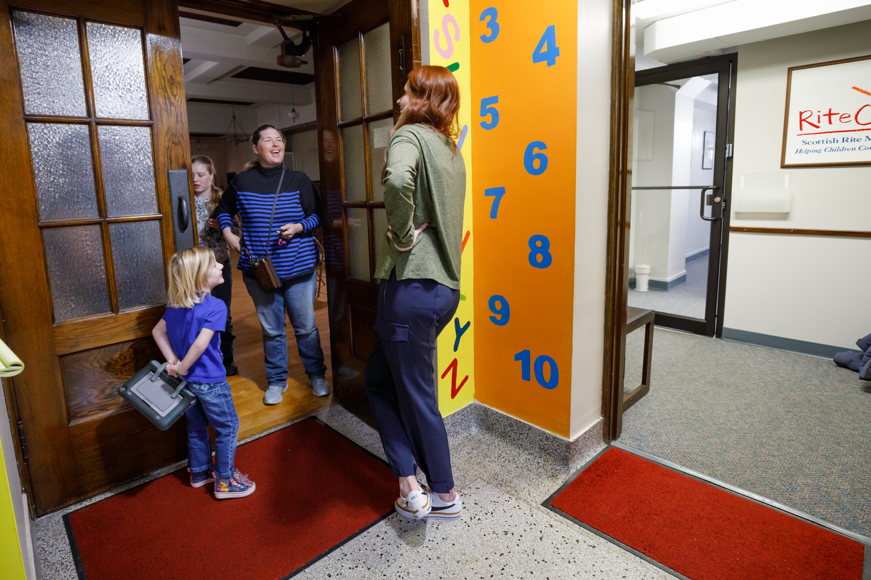 Hannah and her speech therapist excitedly greet each other in the doorway of the clinic.