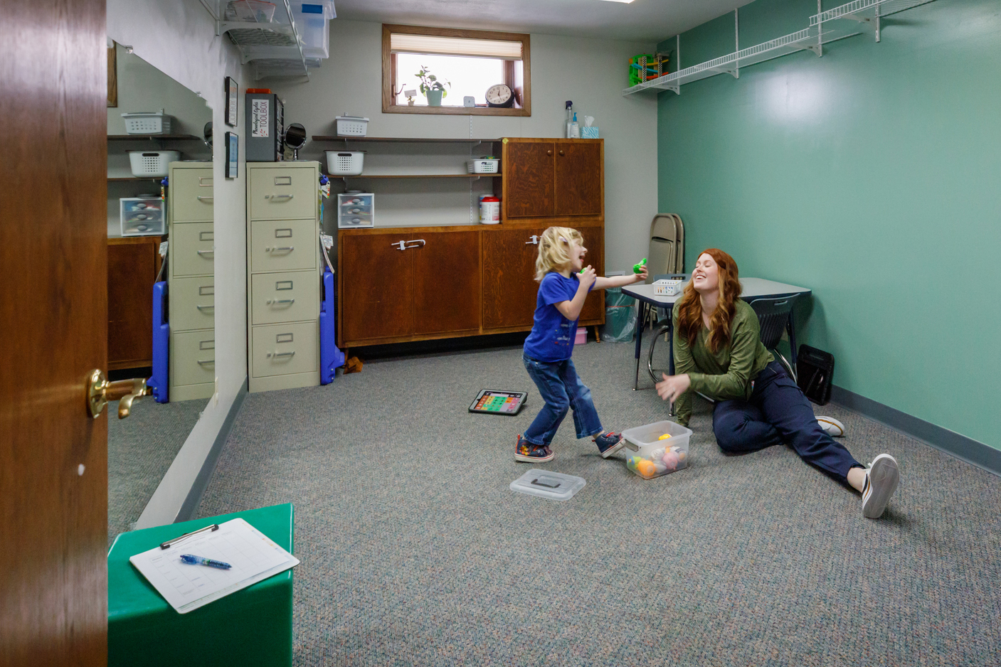 Therapist and young client play together in a therapy room.