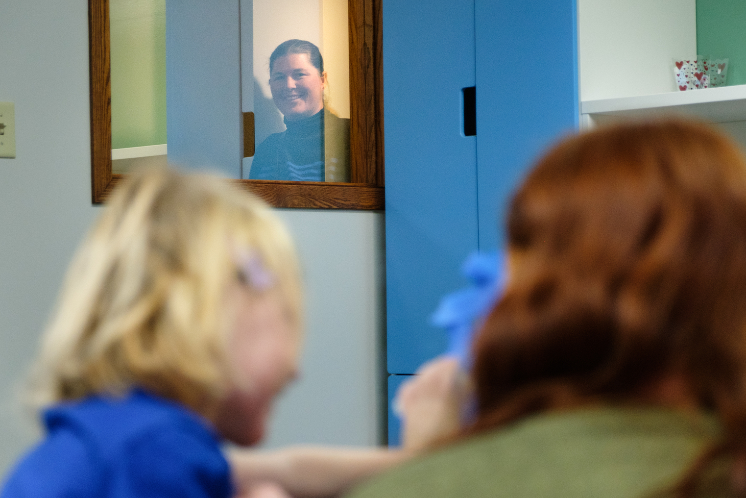 Mom observes her daughter's therapy session through a window.