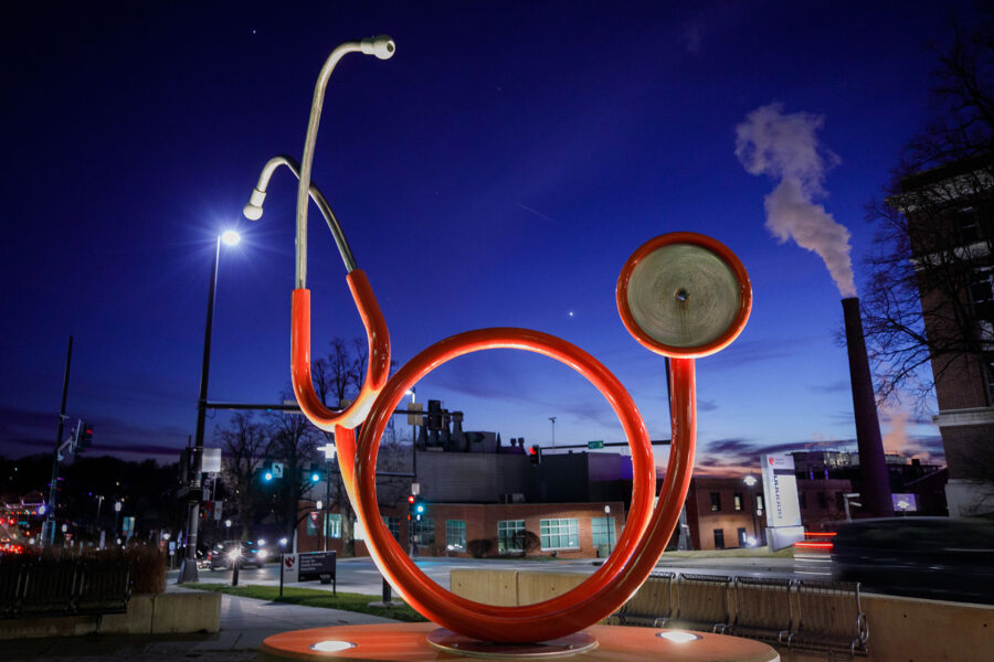 An image of the Sorrell Center's red stethoscope sculpture in the evening, framing the campus to the southwest